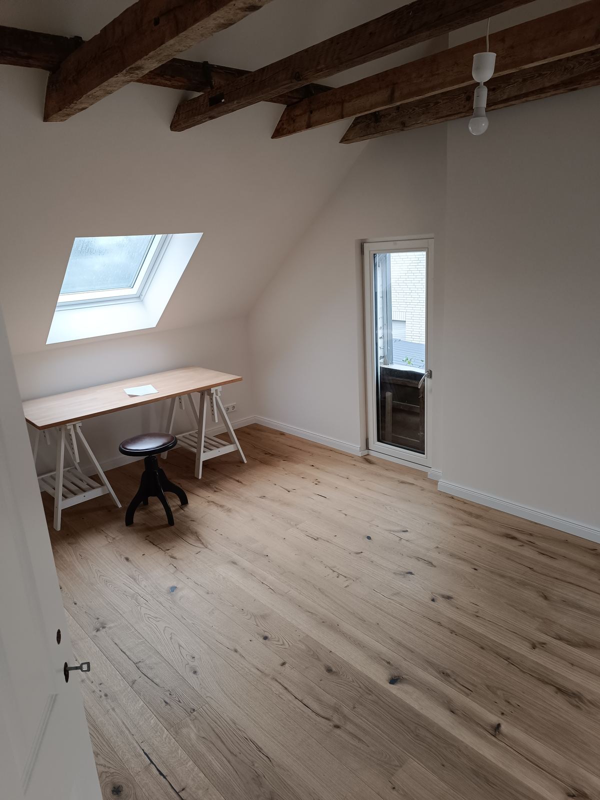 Fertig ausgebautes Dachgeschoss mit sichtbaren Holzbalken