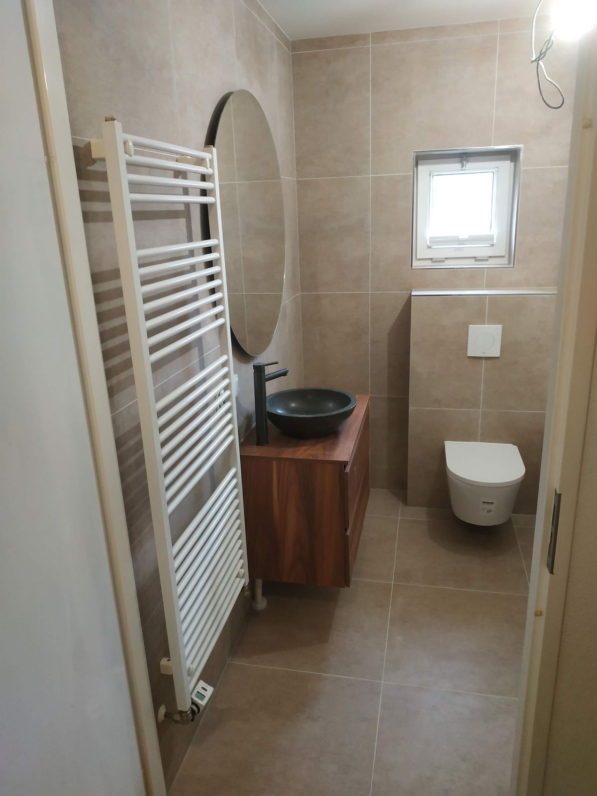 Badezimmer mit rundem Spiegel und Waschtisch